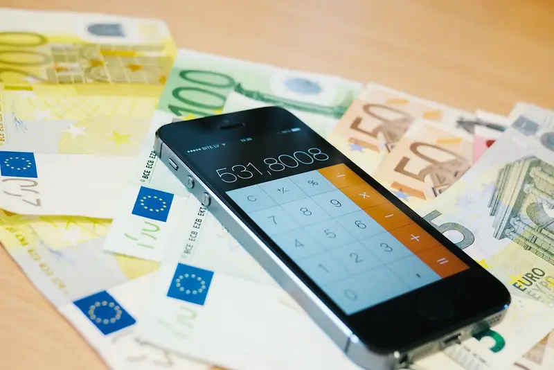 Smartphone met rekenmachine op een stapel eurobiljetten