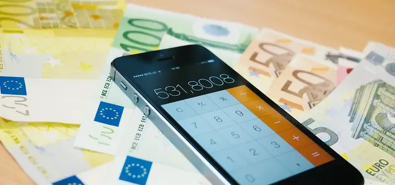 Smartphone met rekenmachine op een stapel eurobiljetten