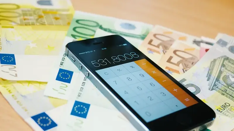 Smartphone met rekenmachine op een stapel eurobiljetten