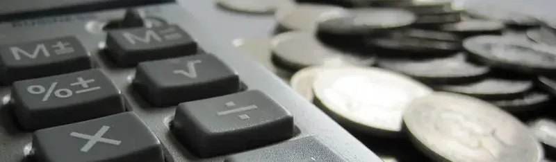 Rekenmachine naast een stapel munten op een bureau, symbool voor persoonlijke financiën