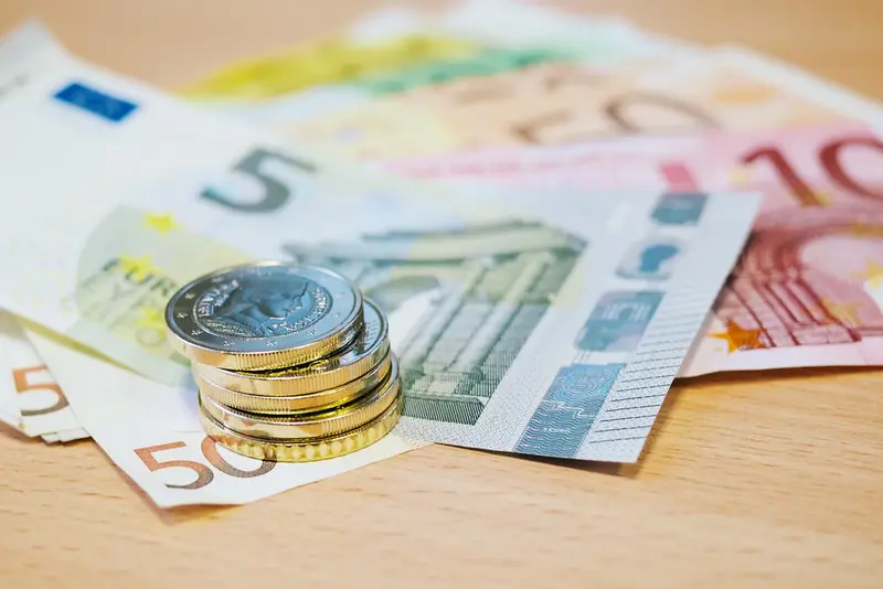 Stapel euromunten op waaier van eurobiljetten