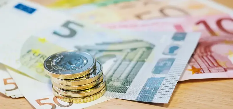 Stapel euromunten op waaier van eurobiljetten