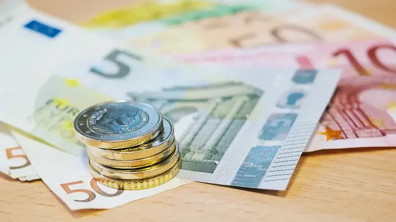 Stapel euromunten op waaier van eurobiljetten