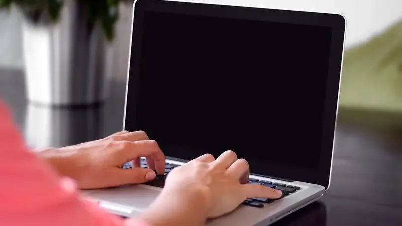Handen van een zelfstandig ondernemer die aan het typen zijn op een laptop aan een bureau