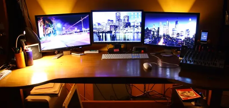 Drie breedbeeldschermen naast elkaar op een bureau